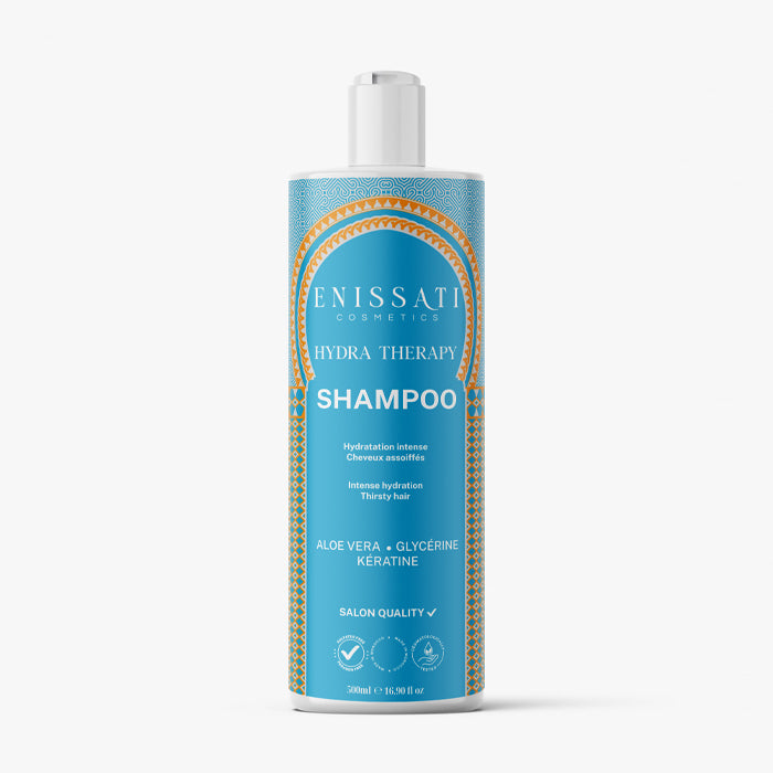 Une bouteille bleue de shampooing Hydra Therapy d'Enissati Cosmetics avec des accents dorés et blancs, contenant de l'aloe vera, de la glycérine et de la kératine, idéale pour une hydratation intense et parfaite pour maintenir le lissage brésilien.  Idéal pour ceux qui recherchent un lissage brésilien et explorent enissati avis. 